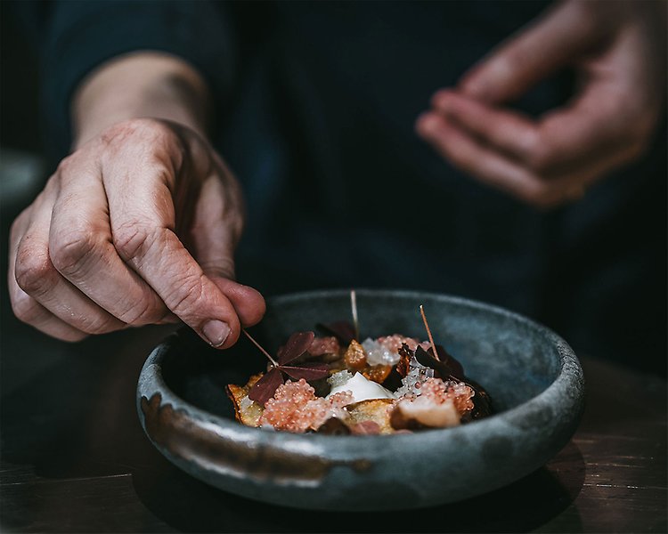 Fotografi av en person som lägger upp mat på en tallrik. Fotograf Rania Rönntoft.